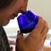 Individual holding a blue glass cup while smelling olive oil during a tasting session. - Olive Oil Times