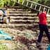 A person carrying a ladder in an olive grove during the harvesting process. - Olive Oil Times