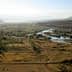 Aerial view of a landscape featuring a river, greenery, and mountains in the background. - Olive Oil Times