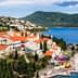 A coastal view of a Mediterranean town with red-roofed buildings and a blue sea. - Olive Oil Times