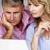 Middle-aged couple closely examining content on a laptop screen in a home setting. - Olive Oil Times