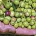 Two hands holding a mix of green and purple olives with leaves. - Olive Oil Times