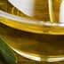 Close-up of a glass bowl filled with olive oil, surrounded by olives and olive leaves. - Olive Oil Times