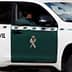 A Guardia Civil vehicle parked with a visible officer inside, featuring a green and white color scheme. - Olive Oil Times