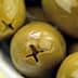 Close-up of green olives in a white bowl with a glossy surface. - Olive Oil Times