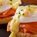 Two servings of Eggs Benedict featuring poached eggs, smoked salmon, and hollandaise sauce on English muffins. - Olive Oil Times