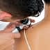 A doctor examining a patient's back with a dermatoscope to assess a skin lesion. - Olive Oil Times