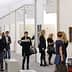 People walking through an art gallery exhibition with various artworks displayed on the walls. - Olive Oil Times