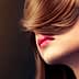 Profile view of a woman with long brown hair covering part of her face and red lips. - Olive Oil Times