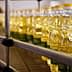 Rows of clear plastic bottles filled with cooking oil on a production line. - Olive Oil Times