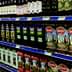 A supermarket shelf displaying various brands of olive oil in bottles and cartons. - Olive Oil Times