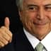 A man with gray hair and a suit giving a thumbs up gesture with a smile. - Olive Oil Times