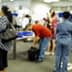 Blurred image of passengers and airport staff in a check-in area with luggage and service counters. - Olive Oil Times