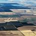 Aerial view of patchwork agricultural fields with varying colors and patterns. - Olive Oil Times