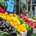 A vibrant display of various vegetables including peppers, zucchini, and tomatoes at a market stall. - Olive Oil Times