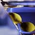 A close-up of a martini glass containing a clear drink and two green olives. - Olive Oil Times