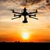 Silhouette of a drone flying against a sunset with clouds in the sky. - Olive Oil Times