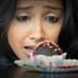 A woman with dark hair gazing intently at a chocolate dessert on a plate. - Olive Oil Times