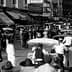 Black and white photograph of a busy boardwalk filled with pedestrians and horse-drawn carriages. - Olive Oil Times