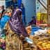 A busy market scene featuring vendors selling baked goods and shoppers browsing at stalls. - Olive Oil Times
