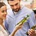 A couple inspecting olive oil bottles while shopping in a supermarket aisle. - Olive Oil Times