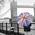 Individual holding a Union Jack umbrella while standing near Tower Bridge in winter. - Olive Oil Times