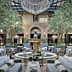 Indoor seating area featuring olive trees, a fountain, and elegant furniture arrangements. - Olive Oil Times
