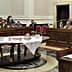 A legislative assembly room with attendees seated at tables during a meeting. - Olive Oil Times