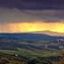 Panoramic view of rolling hills with dark clouds and sunlight breaking through in the distance. - Olive Oil Times