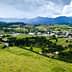 Aerial view of a rural area featuring green fields, a small town, and mountains in the background. - Olive Oil Times
