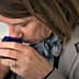 Individual smelling a small blue container during an olive oil tasting session. - Olive Oil Times