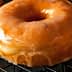 A close-up of a glazed doughnut resting on a wire cooling rack. - Olive Oil Times