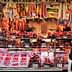 A variety of meats displayed in a market stall with price tags visible. - Olive Oil Times