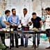 A group of men gathered around a table preparing food outdoors in a rustic setting. - Olive Oil Times