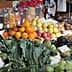 A market stall displaying a variety of fresh fruits and vegetables including oranges, apples, and greens. - Olive Oil Times