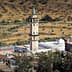 A minaret located in a rural area, surrounded by olive trees and agricultural land. - Olive Oil Times