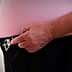 A man adjusting a black belt on his pants with both hands, wearing a pink shirt. - Olive Oil Times
