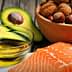 Raw salmon fillet placed on a white surface with a bowl of nuts and sliced avocado in the background. - Olive Oil Times