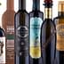 Various bottles of olive oil with distinct labels and designs arranged in a row. - Olive Oil Times