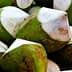 A close-up view of fresh green coconuts with white tops stacked together. - Olive Oil Times