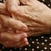Close-up of elderly hands resting on a polka dot fabric surface. - Olive Oil Times