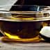 Glass bowl containing coconut oil next to a piece of coconut shell and flesh on a wooden surface. - Olive Oil Times