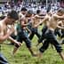 Young men in wet clothing walking in a line during a traditional event on a grassy field. - Olive Oil Times