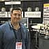 Man standing in front of a booth displaying balsamic vinegar and olive oil products at a trade show. - Olive Oil Times