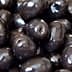 Close-up image of shiny black olives arranged closely together. - Olive Oil Times