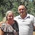 A couple standing together in an olive grove, smiling at the camera. - Olive Oil Times