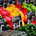 A variety of fresh vegetables including peppers, tomatoes, and cucumbers arranged at a market stall. - Olive Oil Times