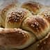 A round loaf of challah bread topped with sesame seeds, showcasing a braided design. - Olive Oil Times