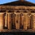 Ancient Greek temple structure with tall columns illuminated at dusk in Paestum, Italy. - Olive Oil Times