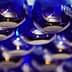 Row of blue glass bottles labeled 'NYIOOC' arranged in a display. - Olive Oil Times